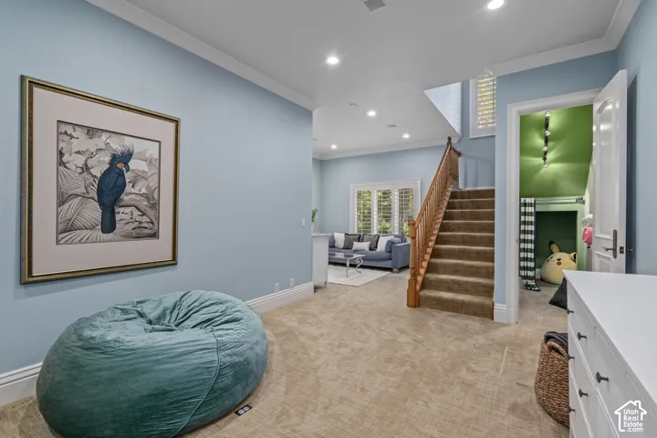 Sitting room with ornamental molding, recessed lighting, stairs, and light carpet