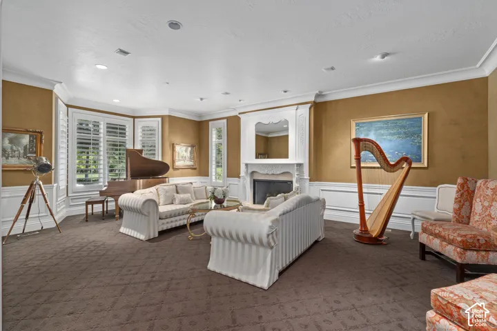Living room with crown molding, carpet, a premium fireplace, a decorative wall, and recessed lighting