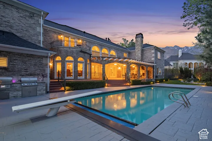 Swimming pool featuring a patio area, a diving board, an outdoor kitchen, and a balcony