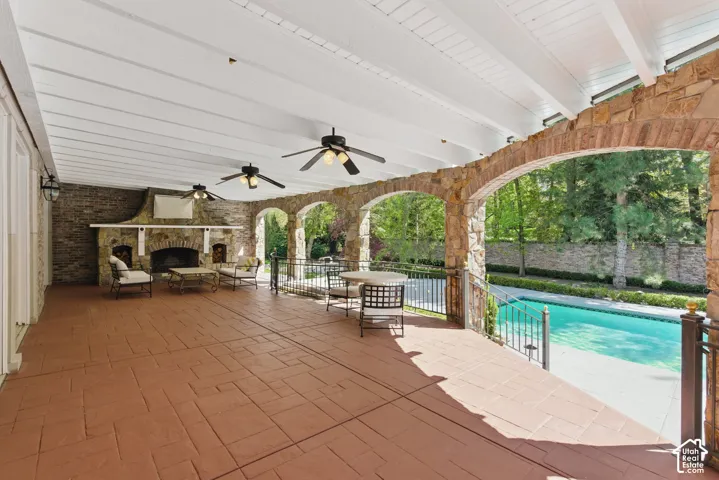 View of patio / terrace featuring an outdoor pool, a ceiling fan, and an outdoor stone fireplace