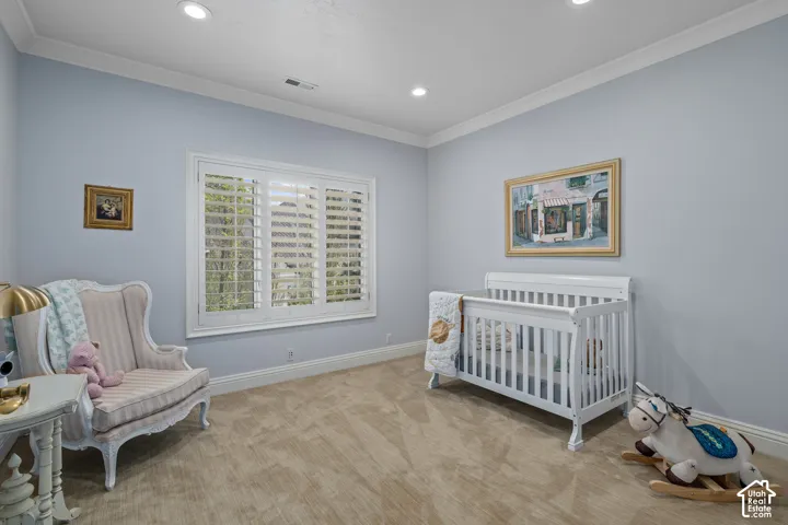 Bedroom featuring ornamental molding, a crib, light colored carpet, and recessed lighting