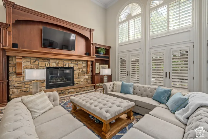 Living room with crown molding, a towering ceiling, and a fireplace