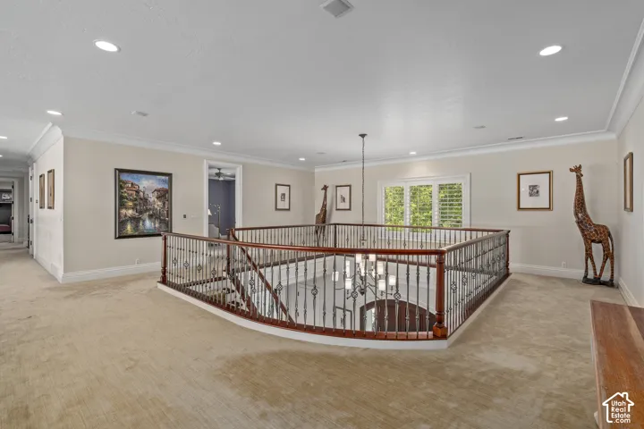 Corridor featuring an upstairs landing, light colored carpet, crown molding, and recessed lighting