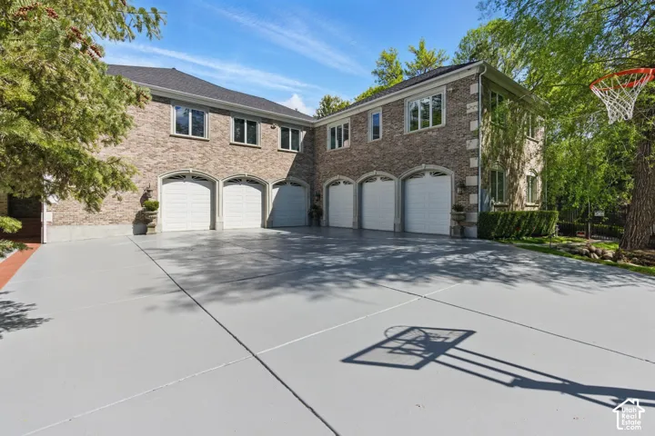 View of front of property featuring driveway, a garage, and brick siding