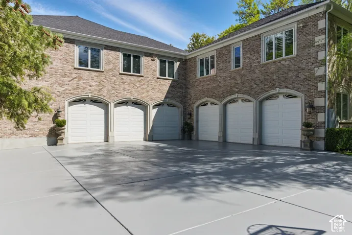 View of front facade featuring a garage, concrete driveway, and brick siding