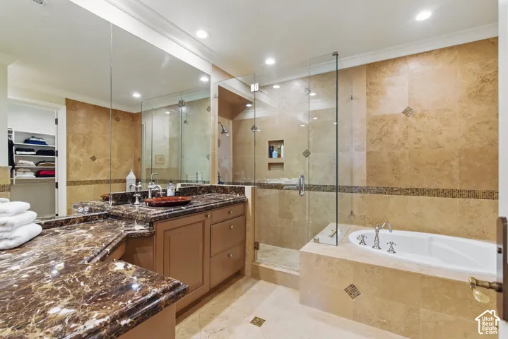 Full bathroom featuring tile walls, a bath, a walk in closet, vanity, and a stall shower