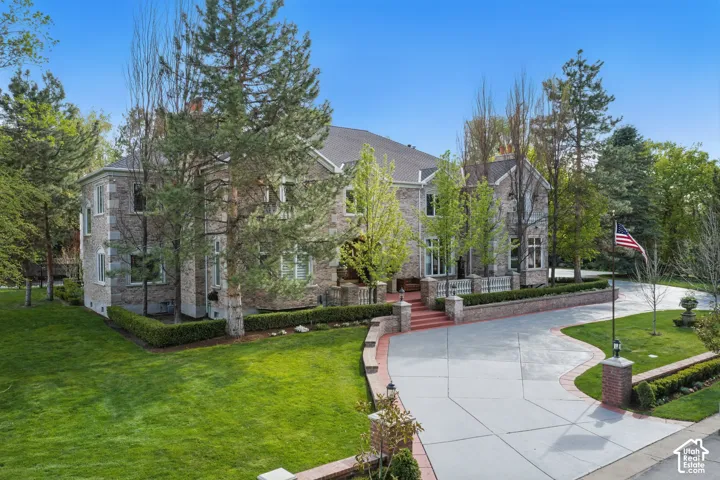 View of front of property with a front lawn, stone siding, and concrete driveway
