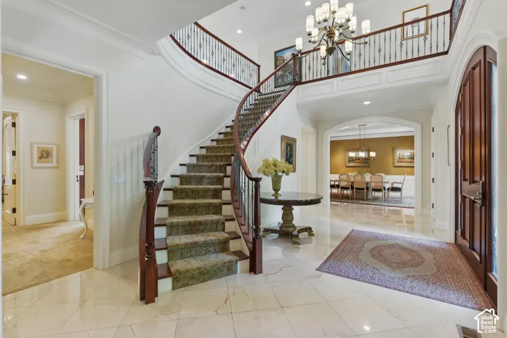 Entryway with crown molding, a chandelier, a high ceiling, recessed lighting, and arched walkways