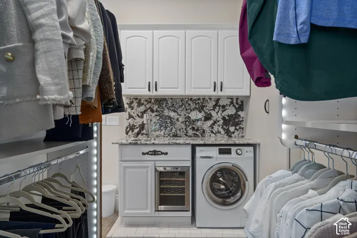 Laundry room with washer / clothes dryer, beverage cooler, light tile patterned floors, and cabinet space