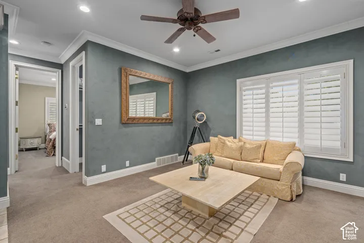 Living area featuring crown molding, light colored carpet, ceiling fan, and recessed lighting