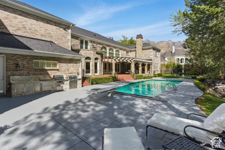 Outdoor pool with area for grilling, a pergola, a patio area, a diving board, and a balcony