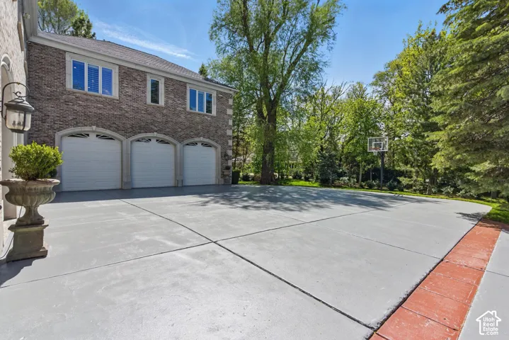 View of side of home with driveway, an attached garage, and brick siding