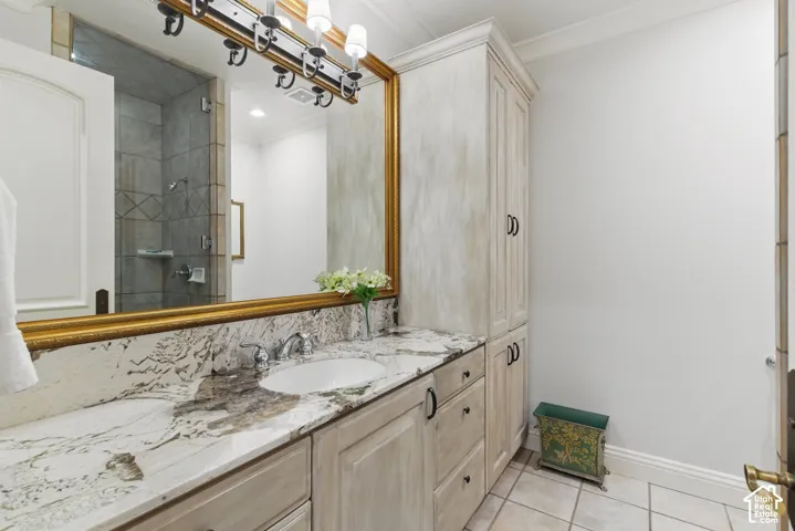 Full bathroom featuring light tile patterned flooring, vanity, ornamental molding, and a stall shower