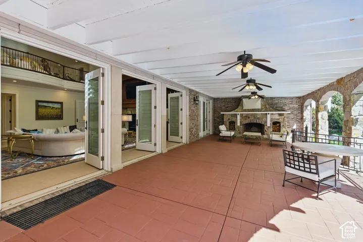 View of patio with an outdoor stone fireplace, a ceiling fan, and outdoor dining area
