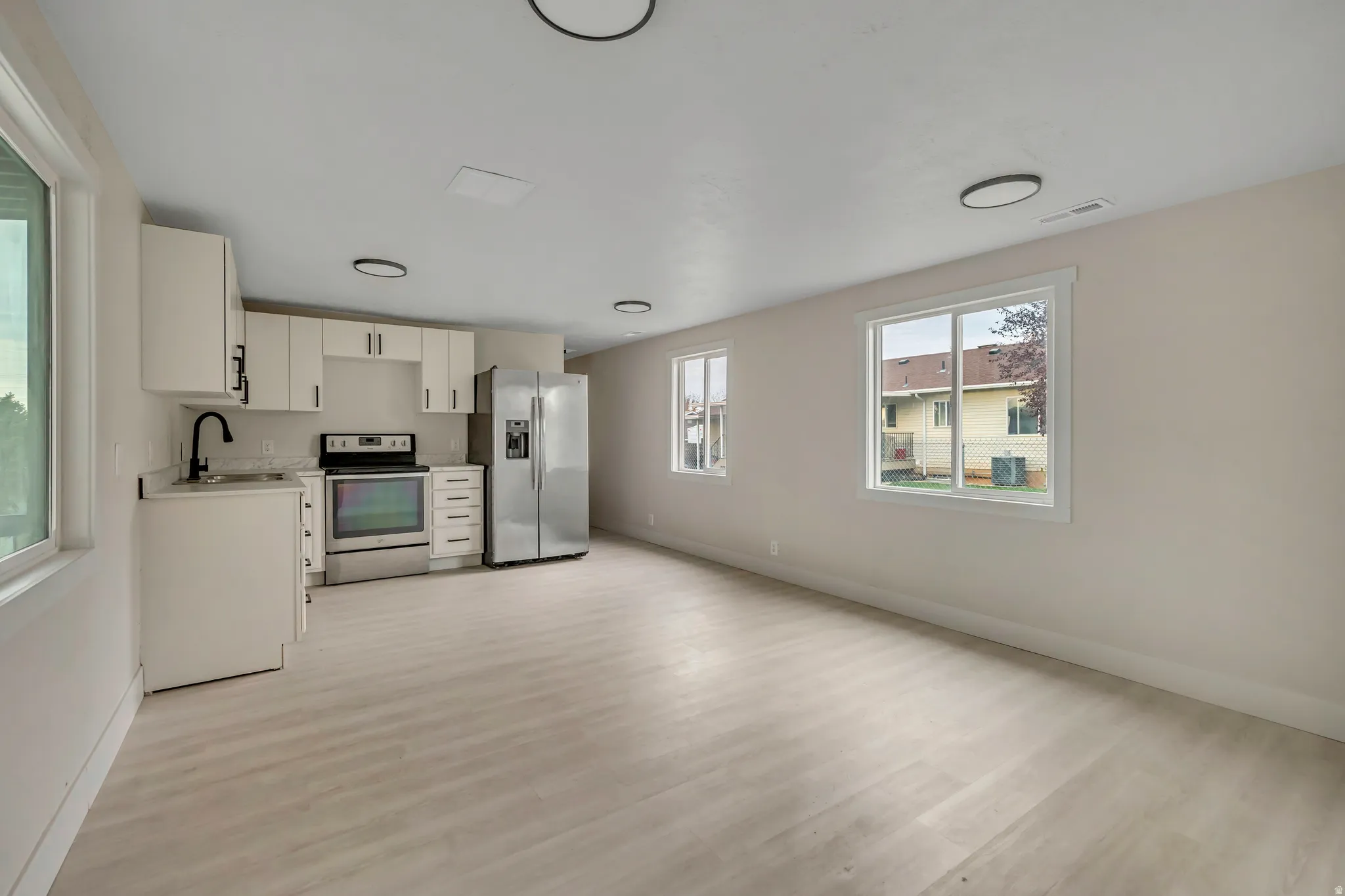 Kitchen with white cabinetry, light countertops, appliances with stainless steel finishes, light wood finished floors, and open floor plan