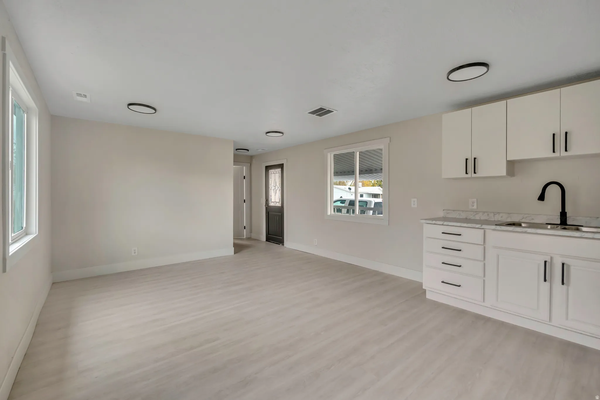Kitchen featuring white cabinets, light wood-type flooring, and light stone countertops