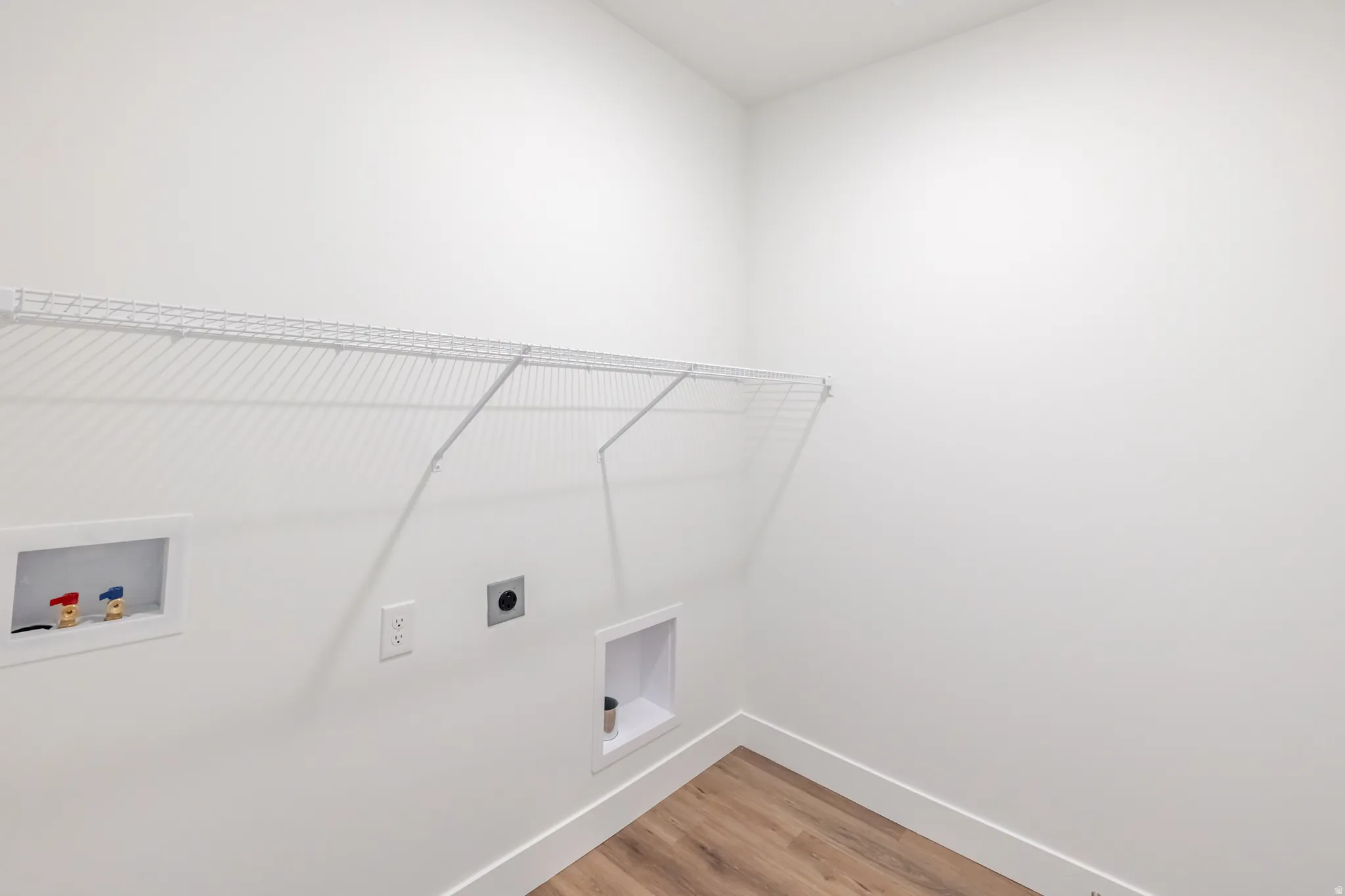 Laundry area with hookup for a washing machine, light wood-style flooring, and electric dryer hookup