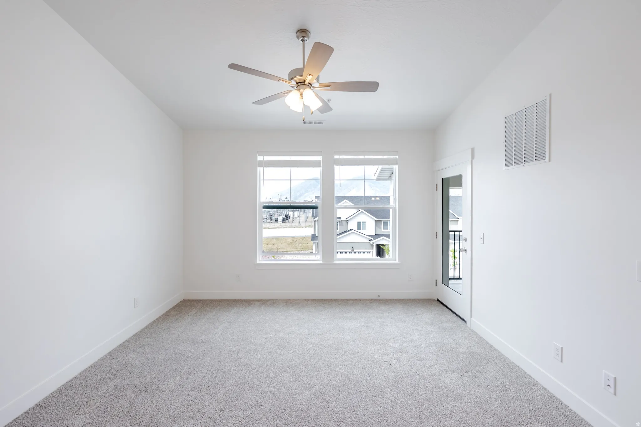Carpeted spare room with ceiling fan and baseboards