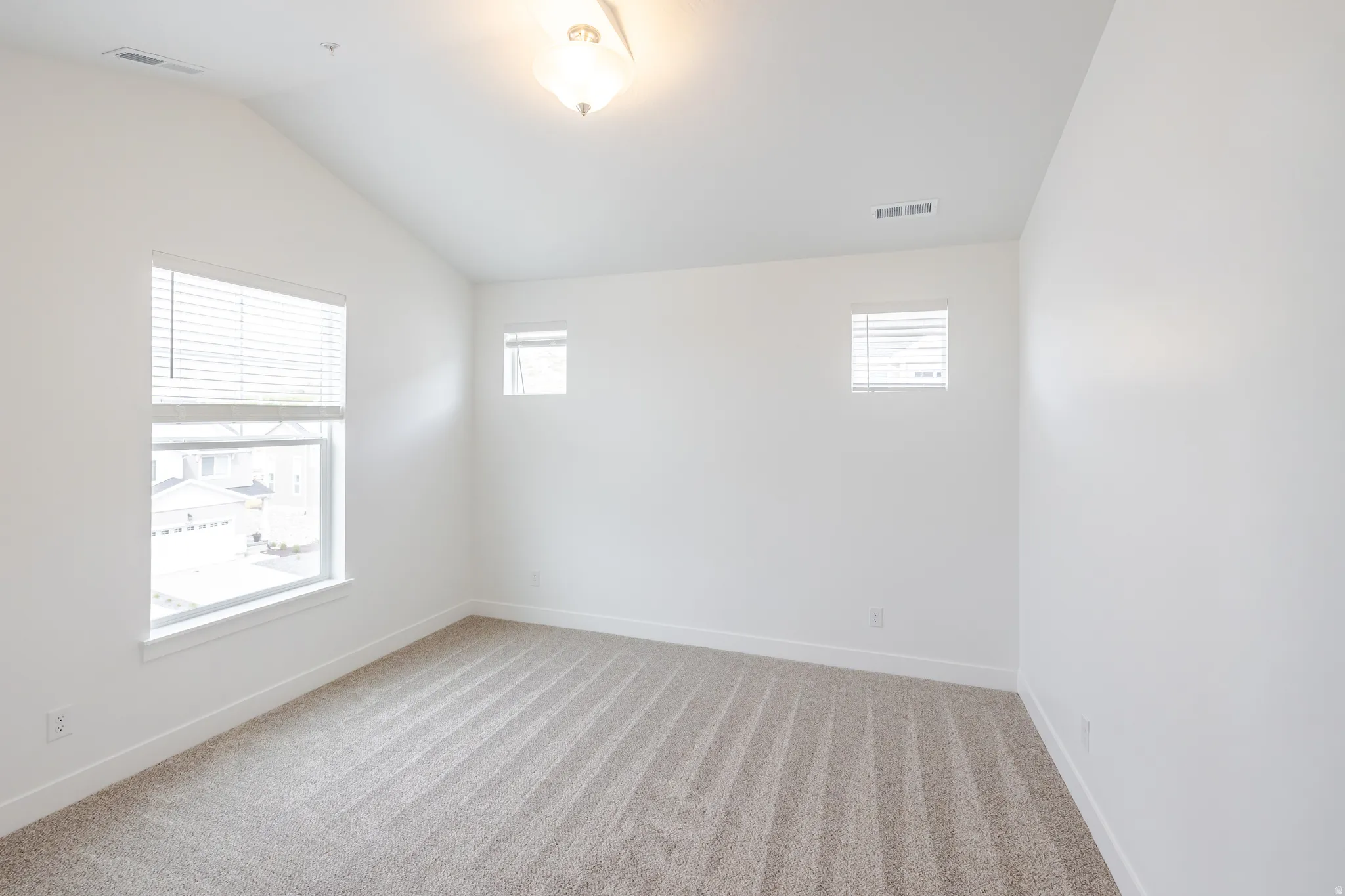 Unfurnished room with light colored carpet and lofted ceiling