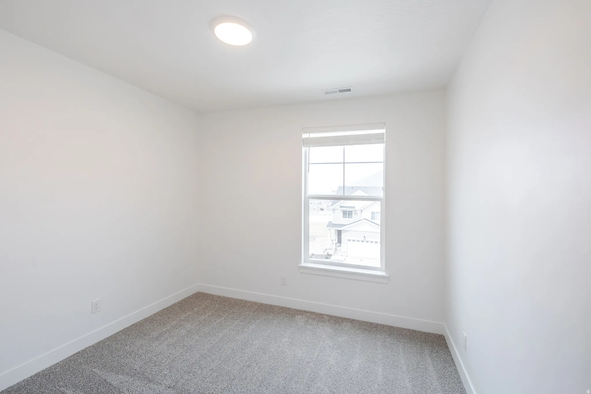 Empty room with light colored carpet and baseboards