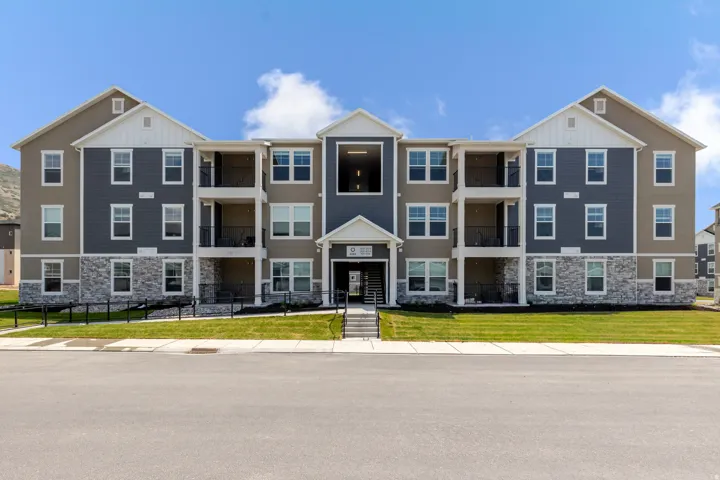 Modern multi-story building featuring gray siding, stone accents, and white trim