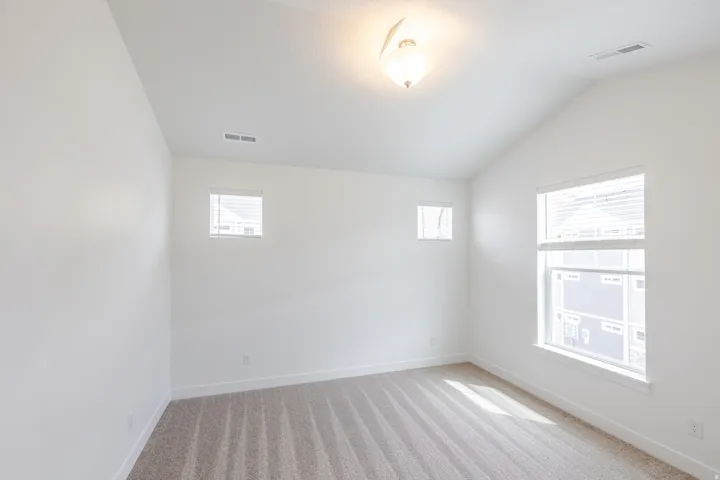 Unfurnished room with vaulted ceiling and light colored carpet