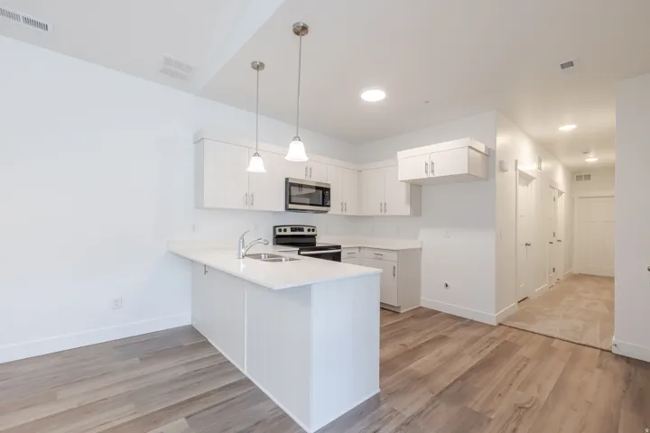 Kitchen featuring white cabinets, light wood-type flooring, stainless steel appliances, and a peninsula