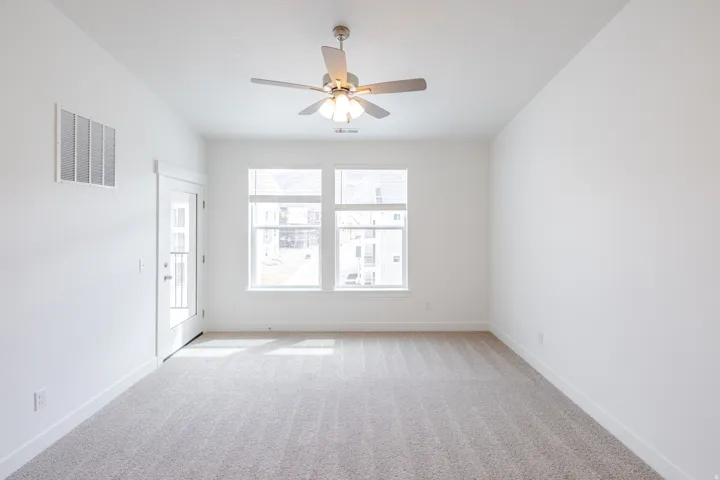 Empty room with light colored carpet and ceiling fan