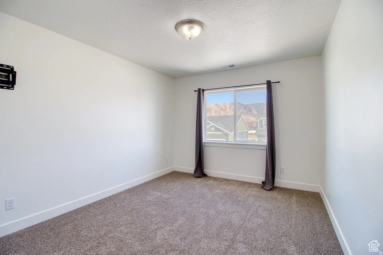 Carpeted empty room with baseboards and a textured ceiling