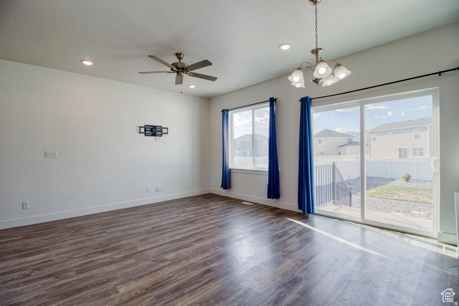 Spare room featuring dark wood-style flooring, ceiling fan, a chandelier, a textured ceiling, and recessed lighting