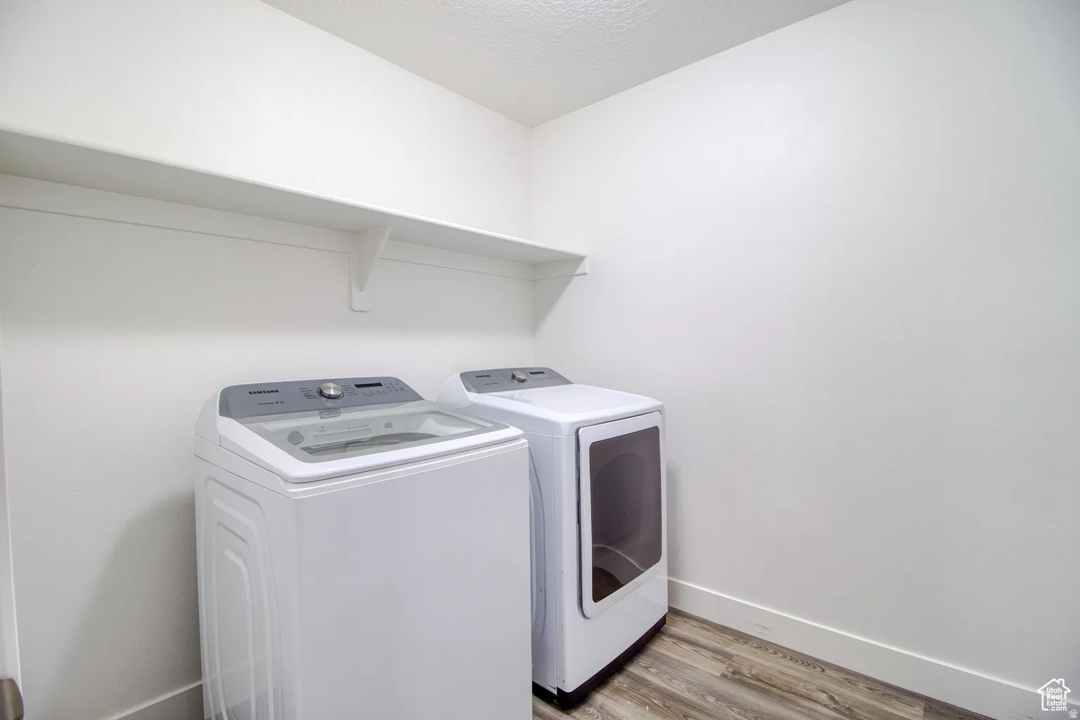 Washroom featuring light wood-style flooring, washing machine and dryer, and a textured ceiling