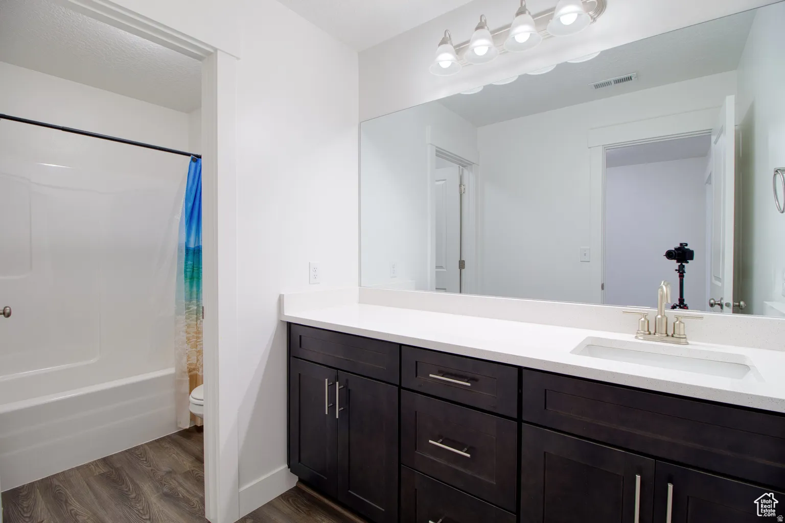 Full bath with vanity, dark wood finished floors, and shower / bath combo
