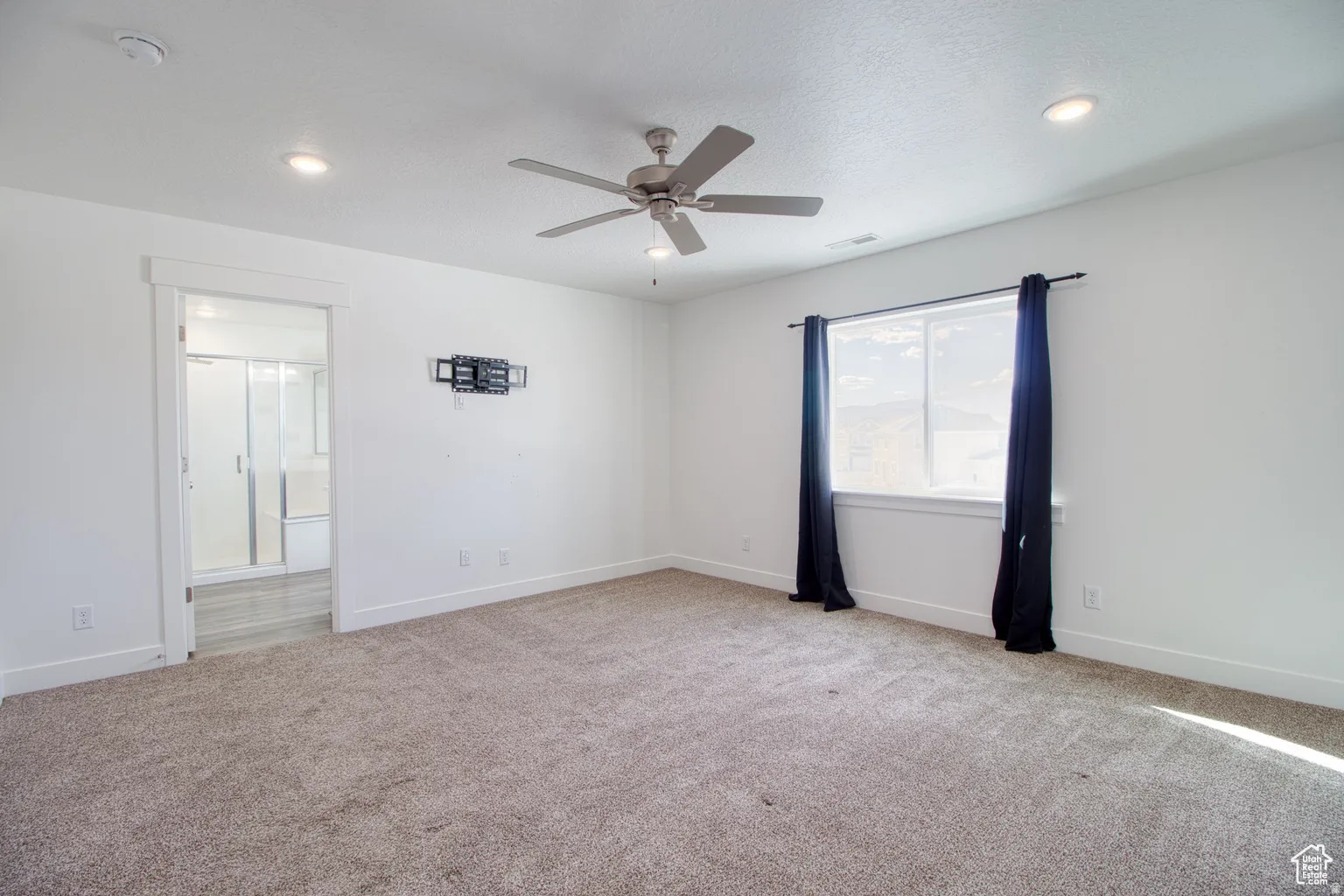 Unfurnished room with light carpet, a ceiling fan, and a textured ceiling