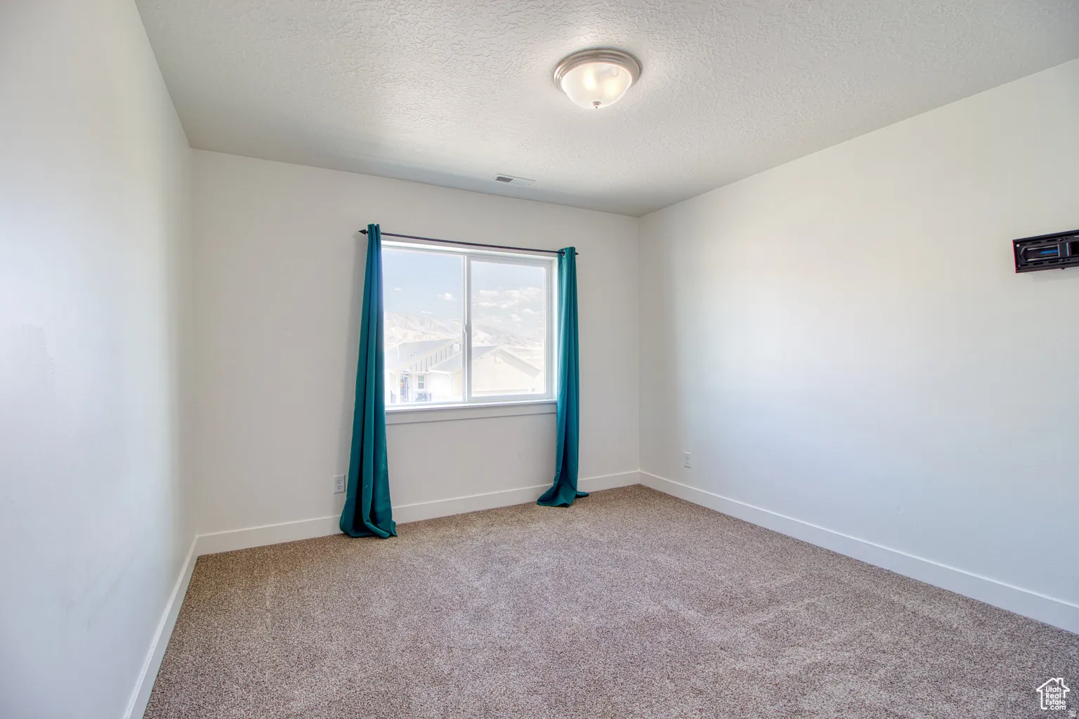 Empty room with light carpet and a textured ceiling
