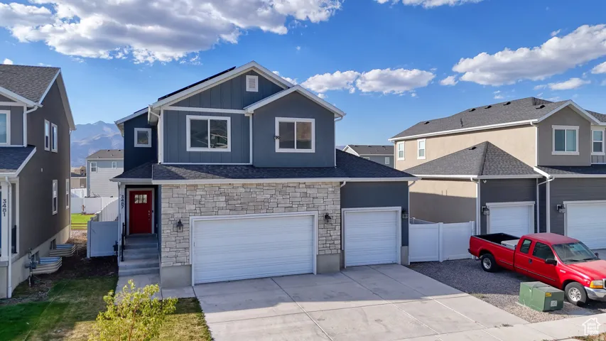 View of front of home with stone siding, concrete driveway, board and batten siding, a residential view, and a garage