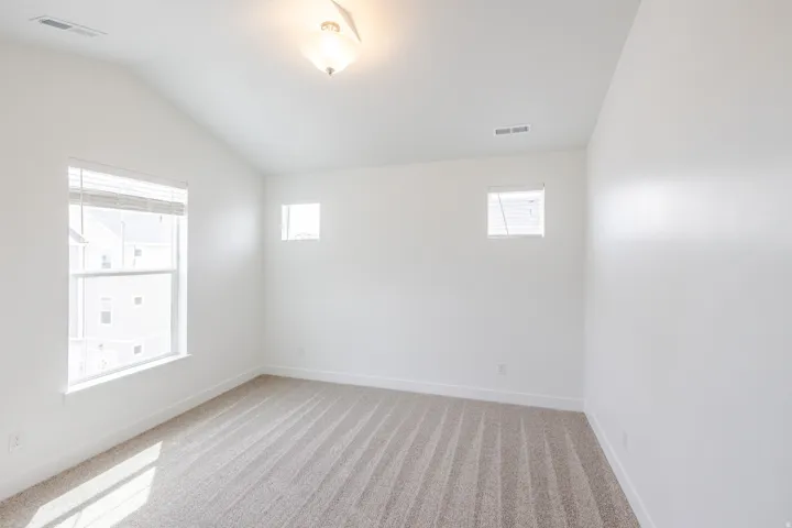 Spare room featuring light colored carpet and vaulted ceiling