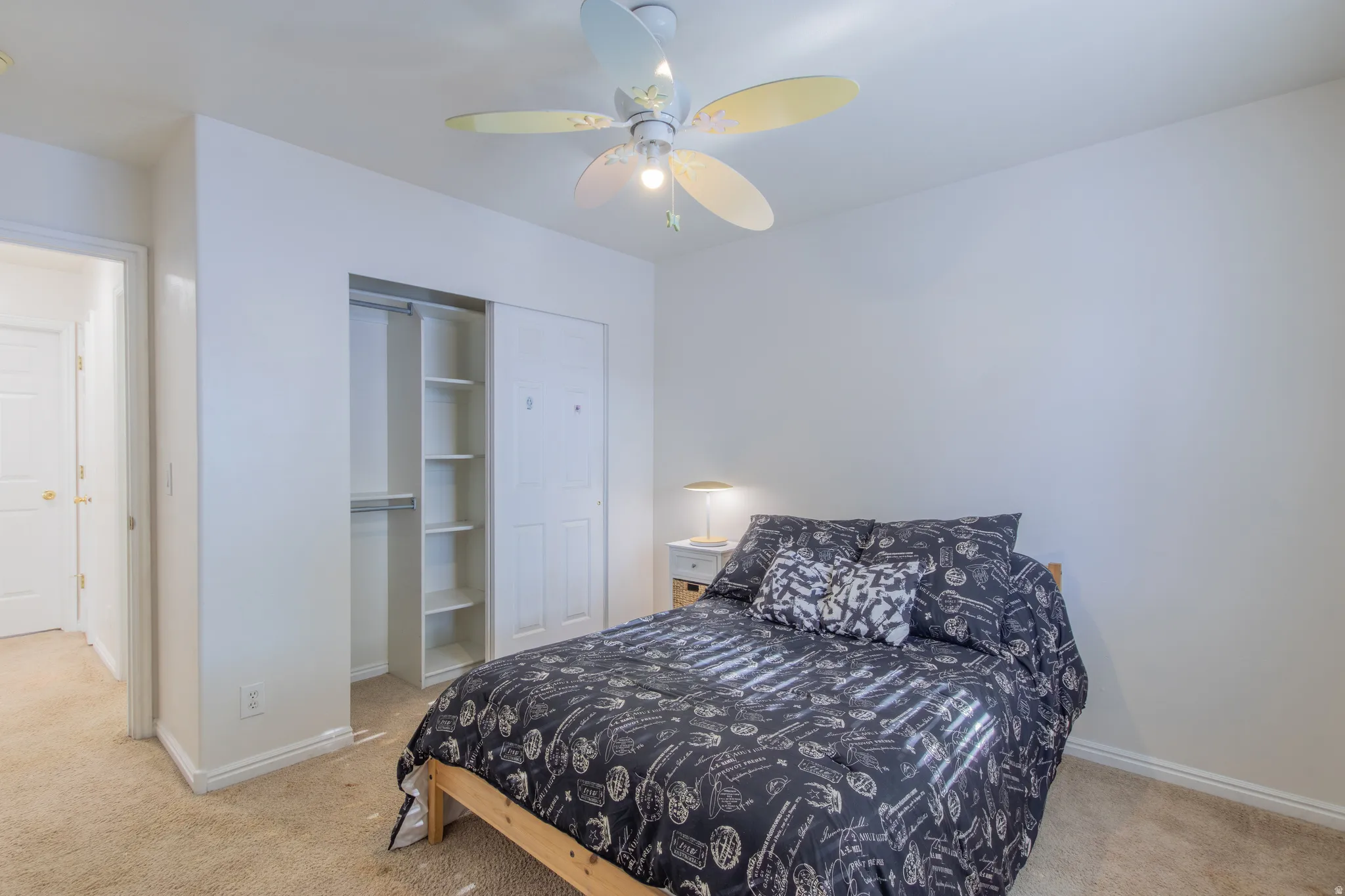 Bedroom featuring light colored carpet, a closet, and a ceiling fan
