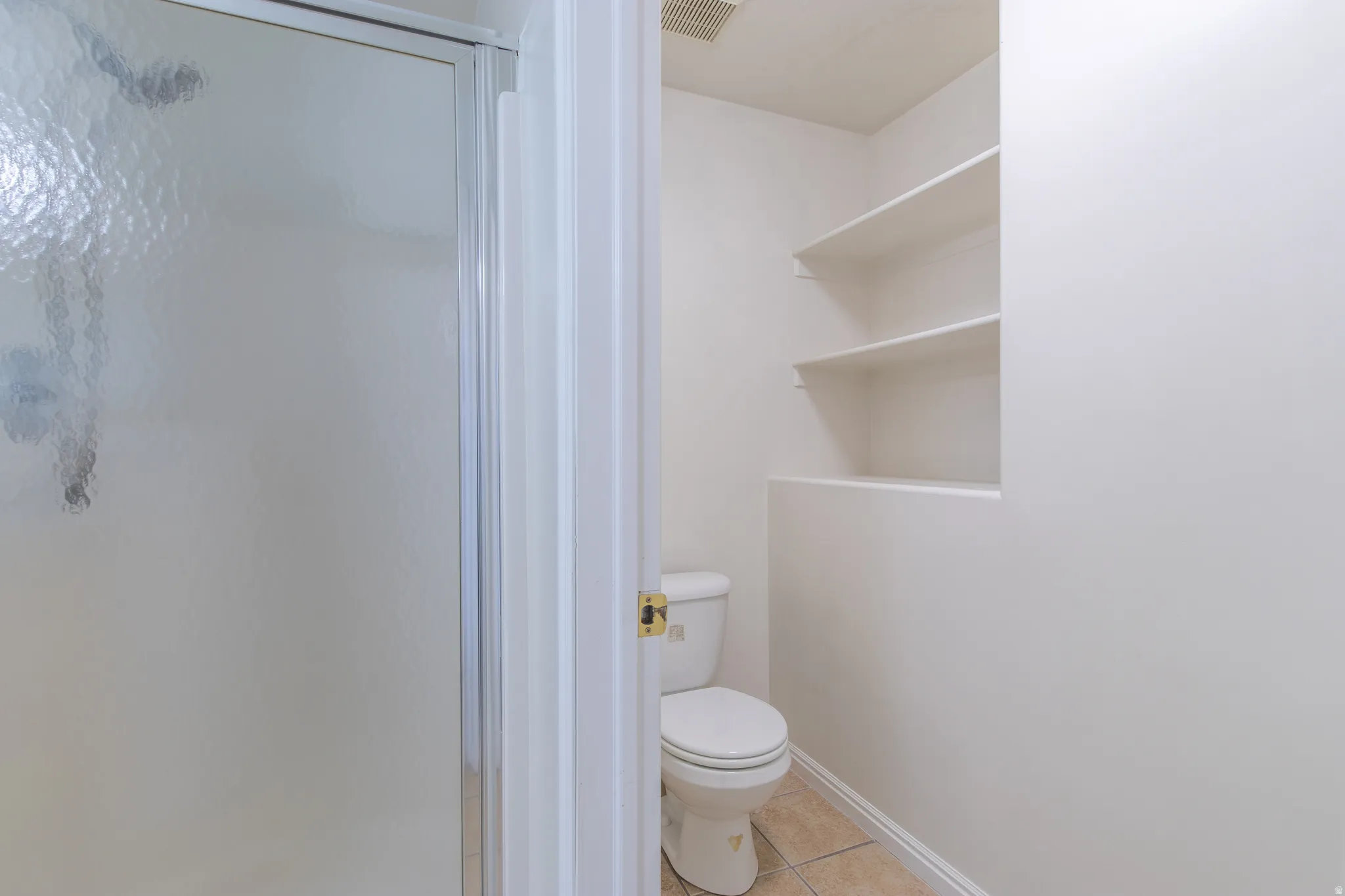 Full bath with light tile patterned floors and a shower stall