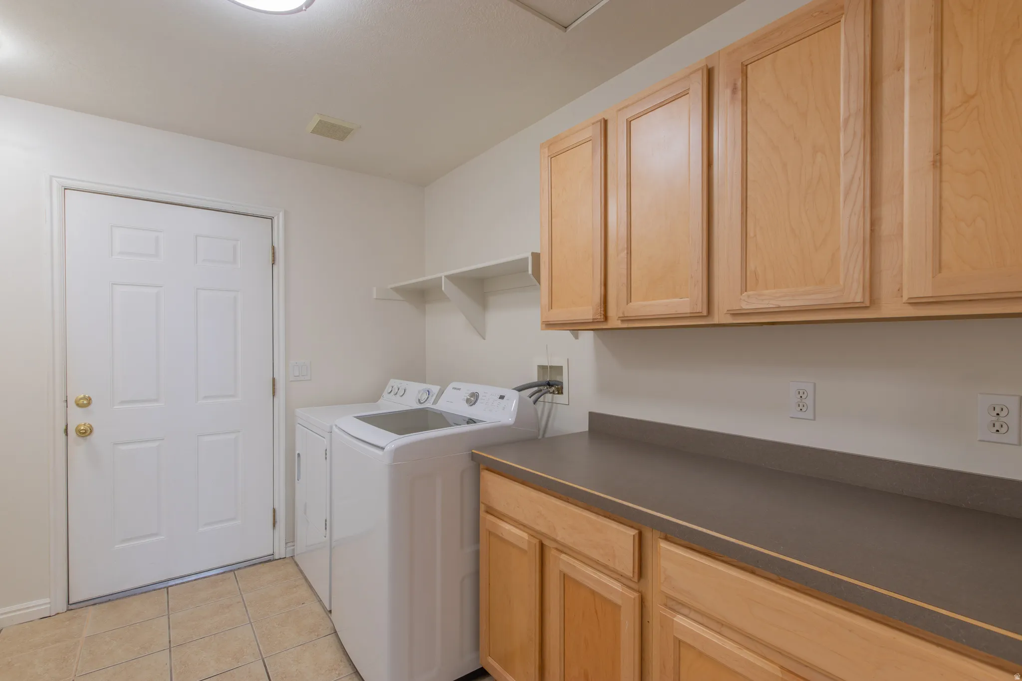 Washroom featuring light tile patterned floors, independent washer and dryer, and cabinet space