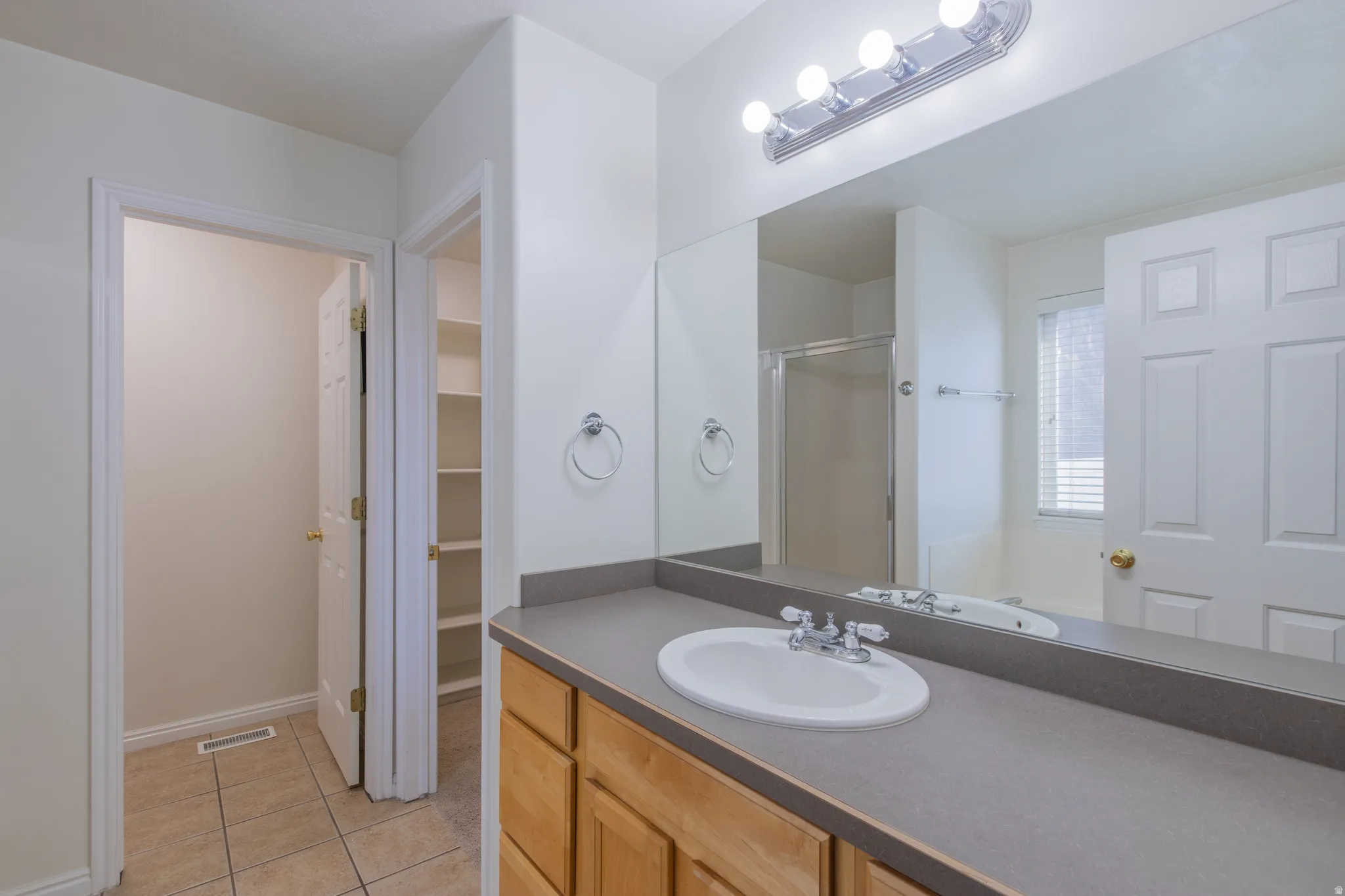 Bathroom featuring light tile patterned floors, a stall shower, vanity, a garden tub, and a walk in closet