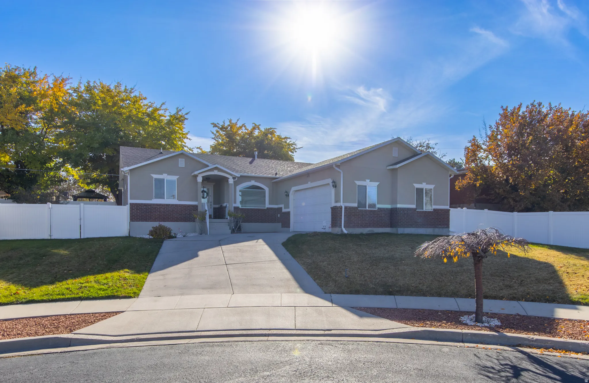 View of front facade featuring brick siding, concrete driveway, an attached garage, and stucco siding