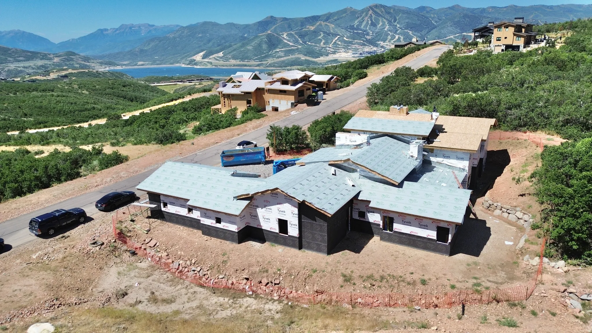New construction property featuring a multi-level roofline, partial exterior sheathing, and a surrounding natural landscape