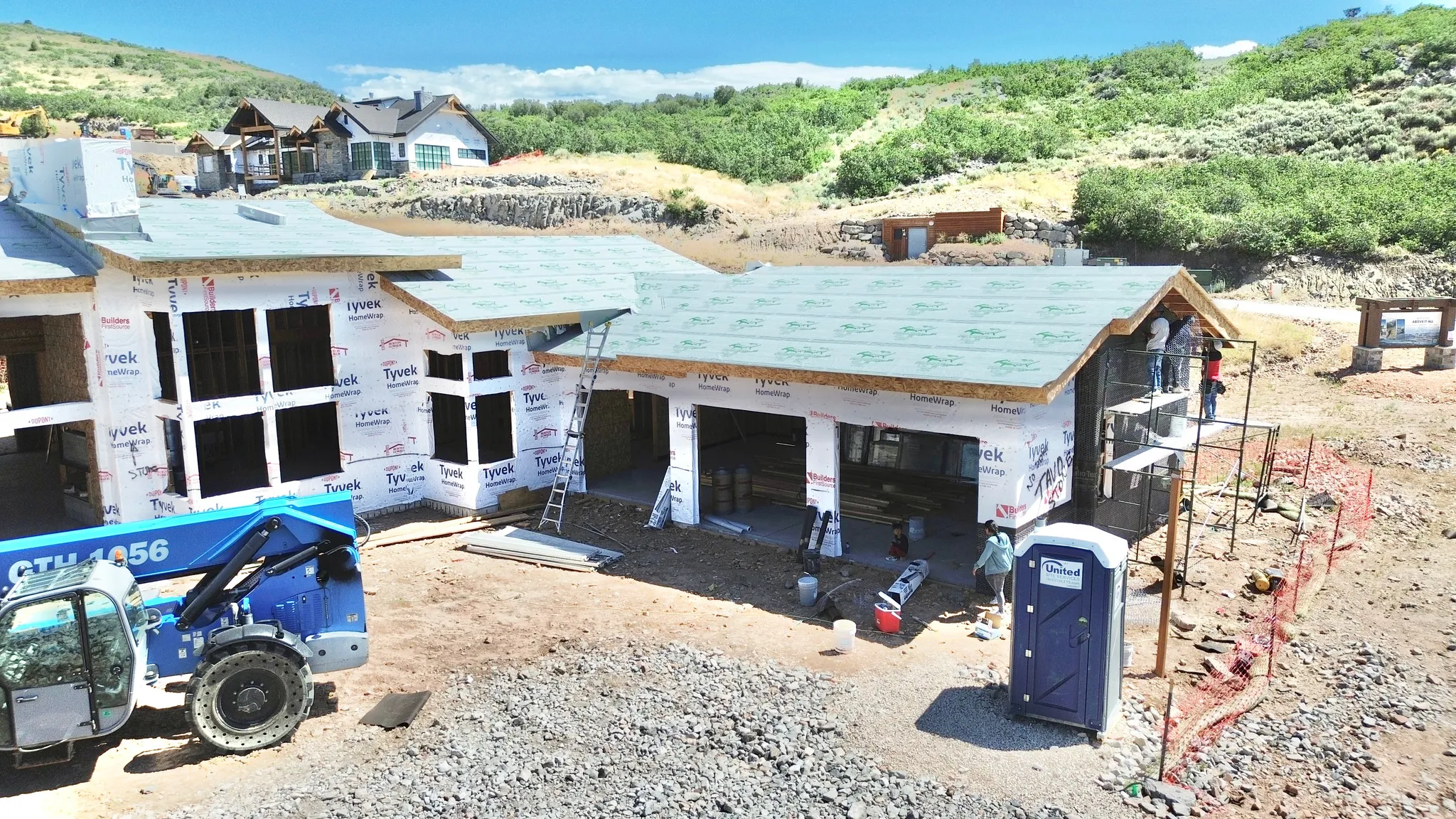 Contemporary architectural design under construction, featuring multiple large window openings, a multi-level roofline, and an integrated garage structure