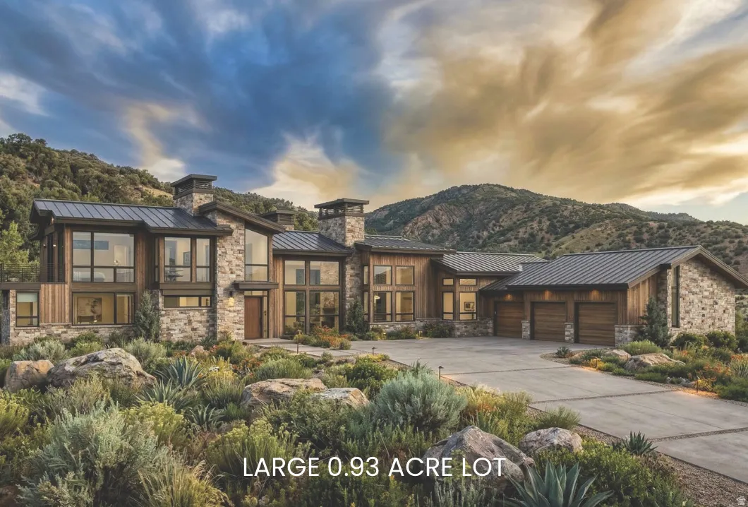 Contemporary home featuring a standing seam roof, stone siding, an attached garage, concrete driveway, and a chimney
