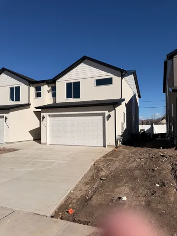 View of front facade with an attached garage, driveway, and stucco siding