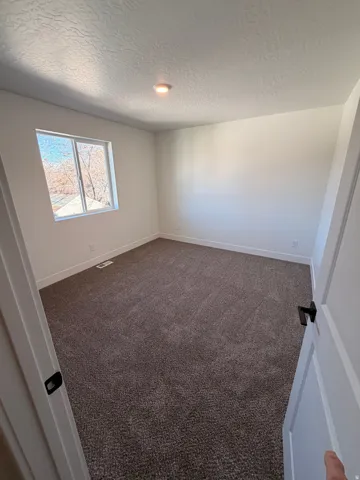 Unfurnished room with dark carpet and a textured ceiling