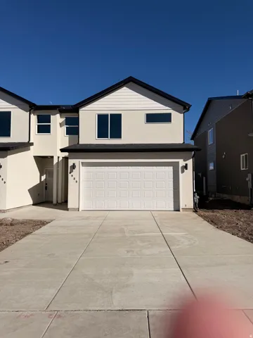 View of front of house with stucco siding, an attached garage, and driveway