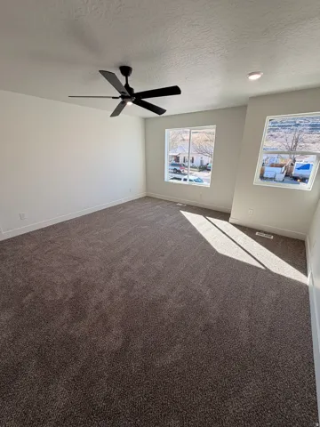 Spare room featuring dark colored carpet, a textured ceiling, and ceiling fan