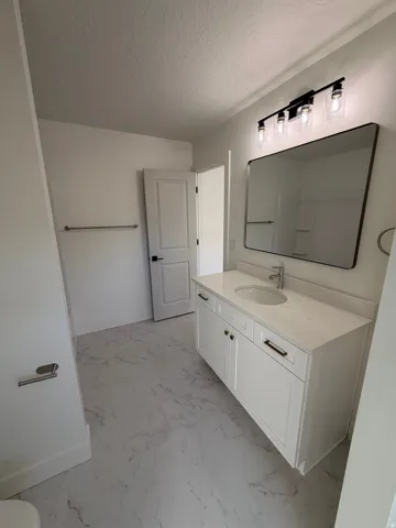 Bathroom featuring vanity, a textured ceiling, and light marble finish floors