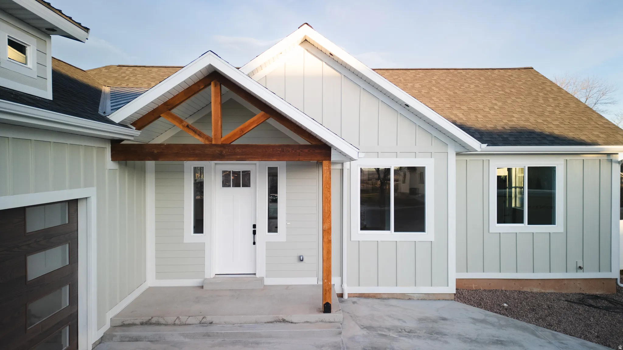 View of exterior entry featuring board and batten siding, roof with shingles, and a porch